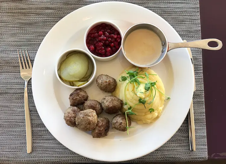 Traditional Swedish meatballs dish, including meatballs with gravy, mashed potatoes, cranberry sauce and pickled cucumbers