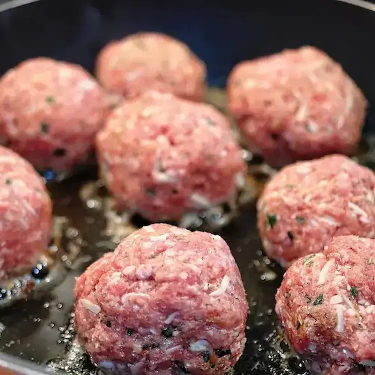 Raw pork or beef meatballs are fried in a skillet with oil