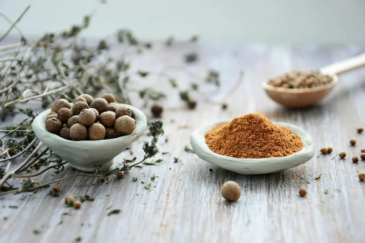 various spices displayed in small bowls on a wooden table