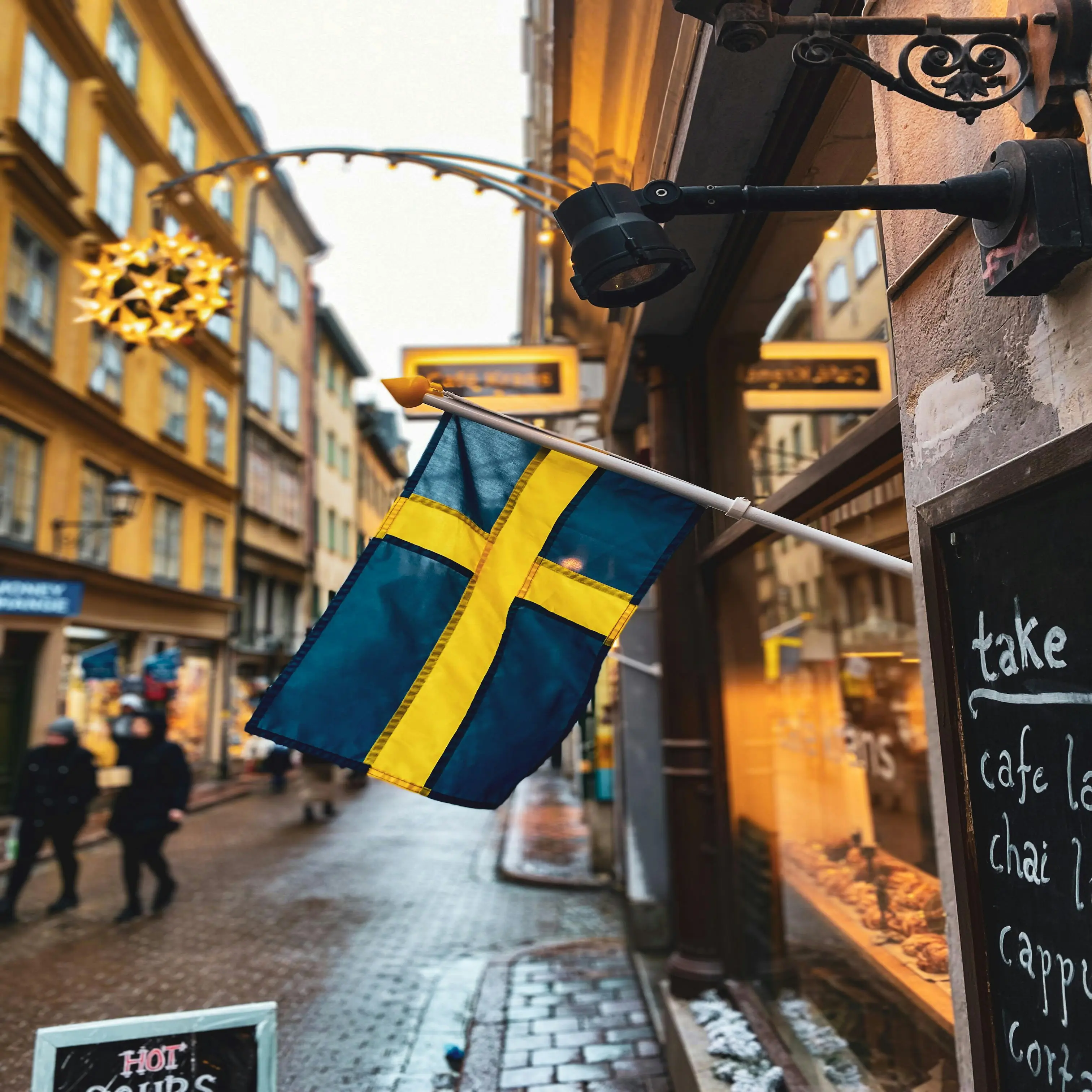 Swedish flag on the side of a building in the street with ambient lighting
